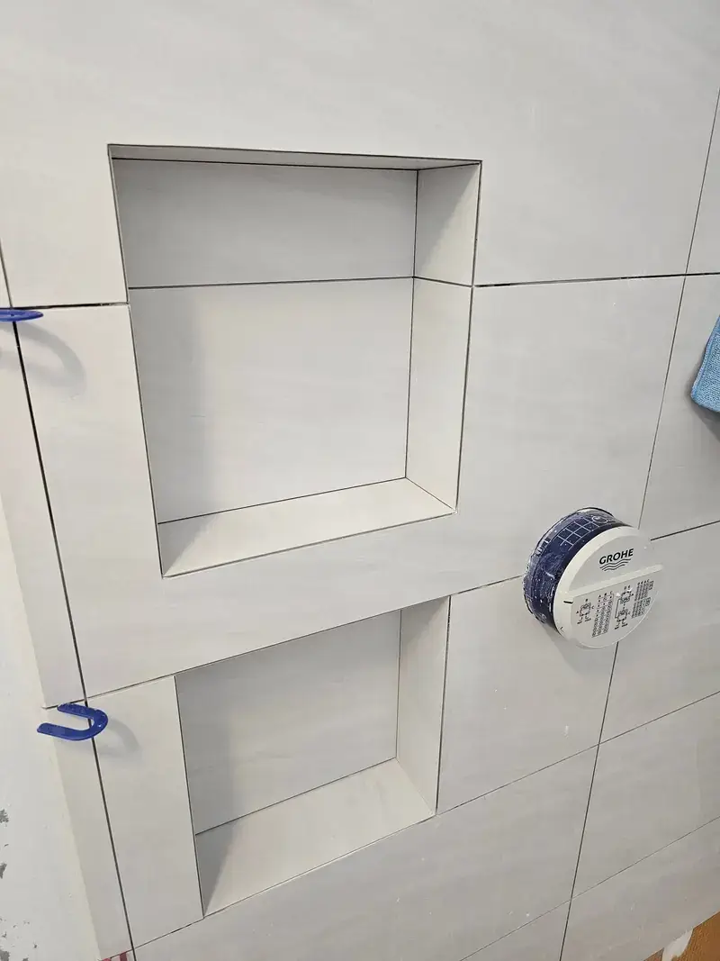Custom-cut tile shampoo shelf set into a shower niche