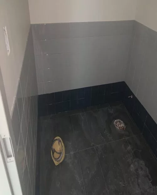 Black ceramic tiles installed over bathroom floor