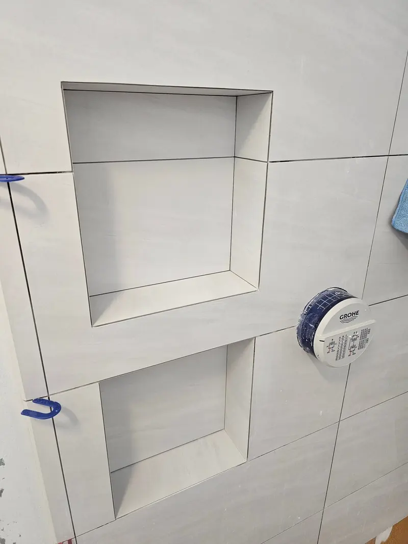 Custom-cut tile shampoo shelf set into a shower niche