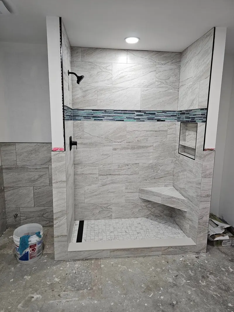 Porcelain marble-look shower walls with mosaic marble tile base, sandstone curb, and inset detailing
