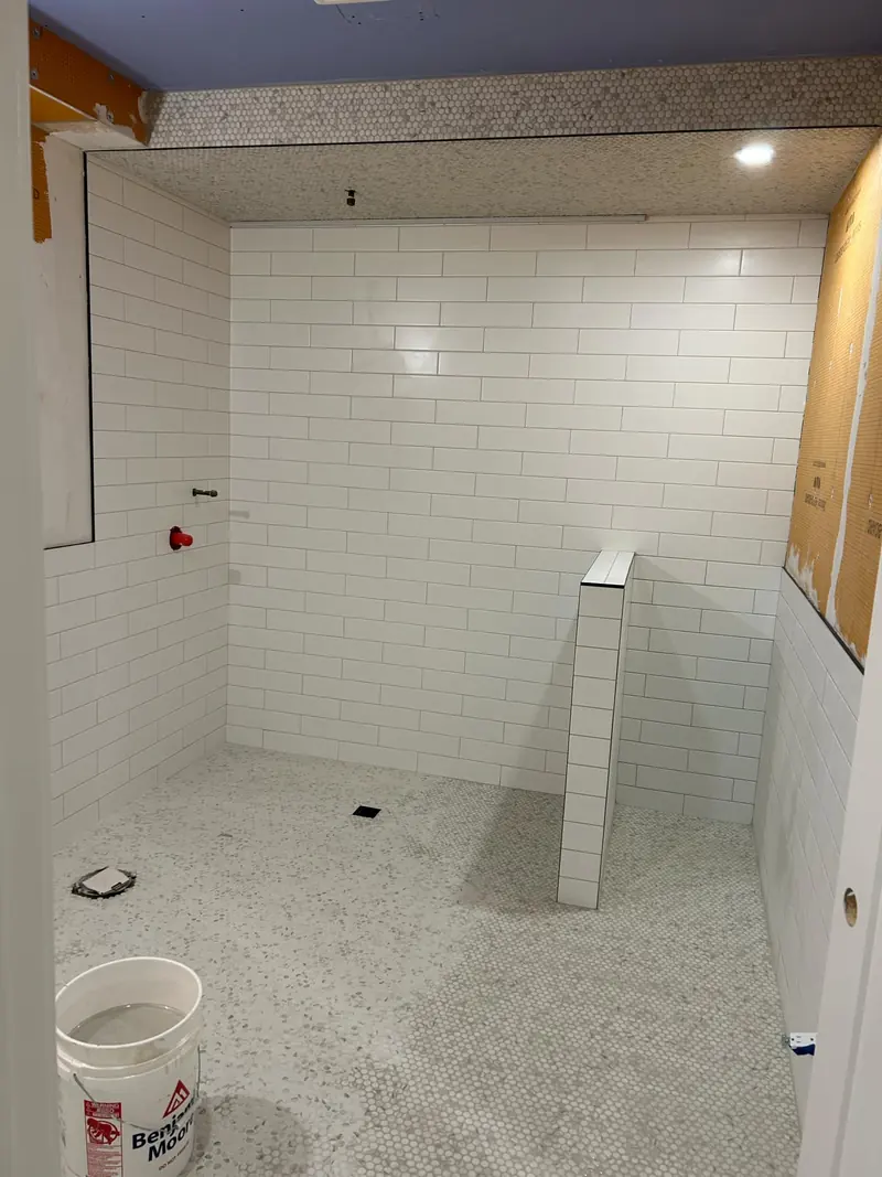 Subway tile in a commercial bathroom with rounded mosaic accent band