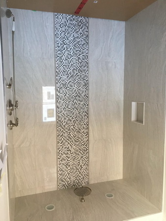 Spacious remodeled bathroom with marble tile, glass shower enclosure, and sleek fixtures